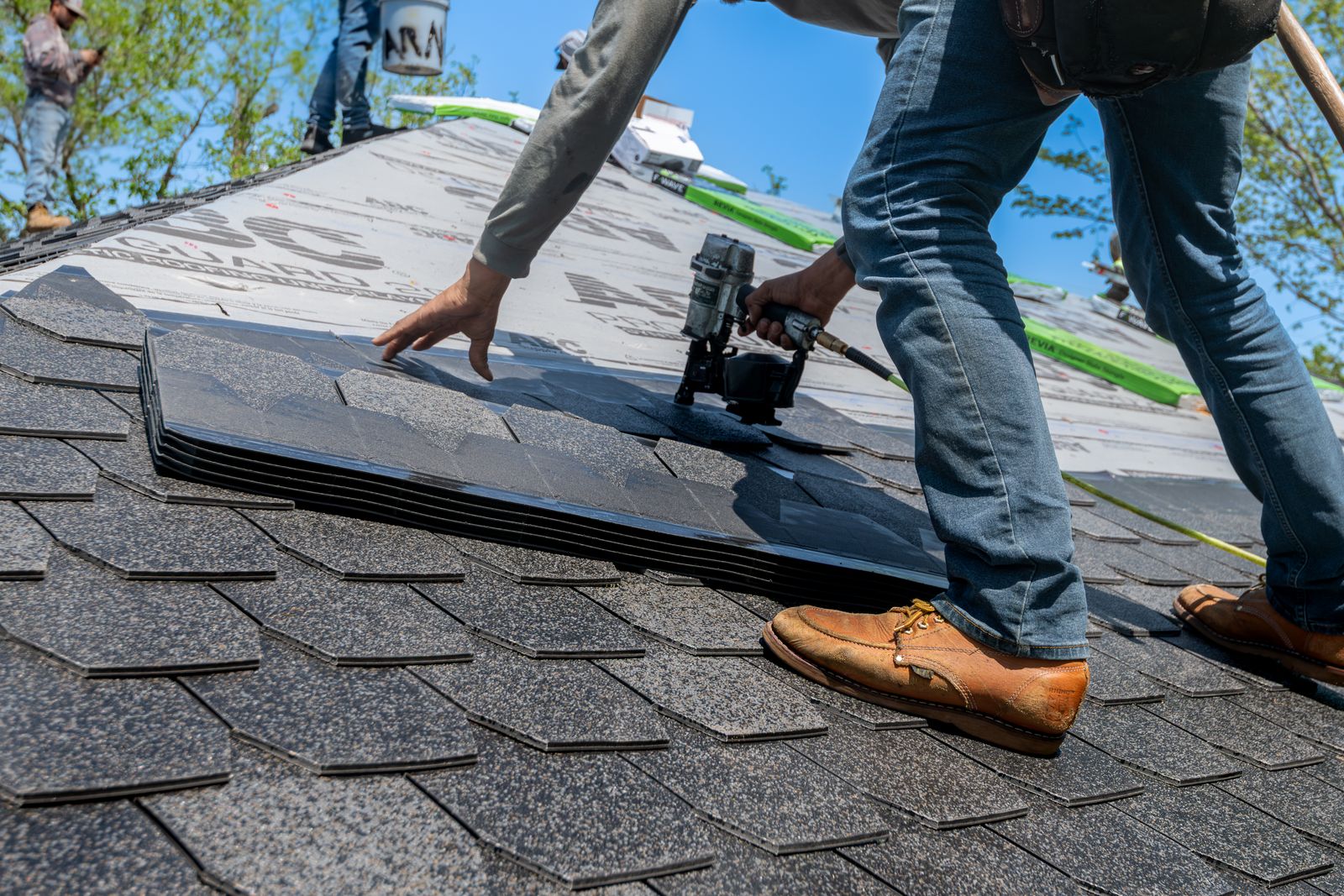 A roofer nailing down new shingles